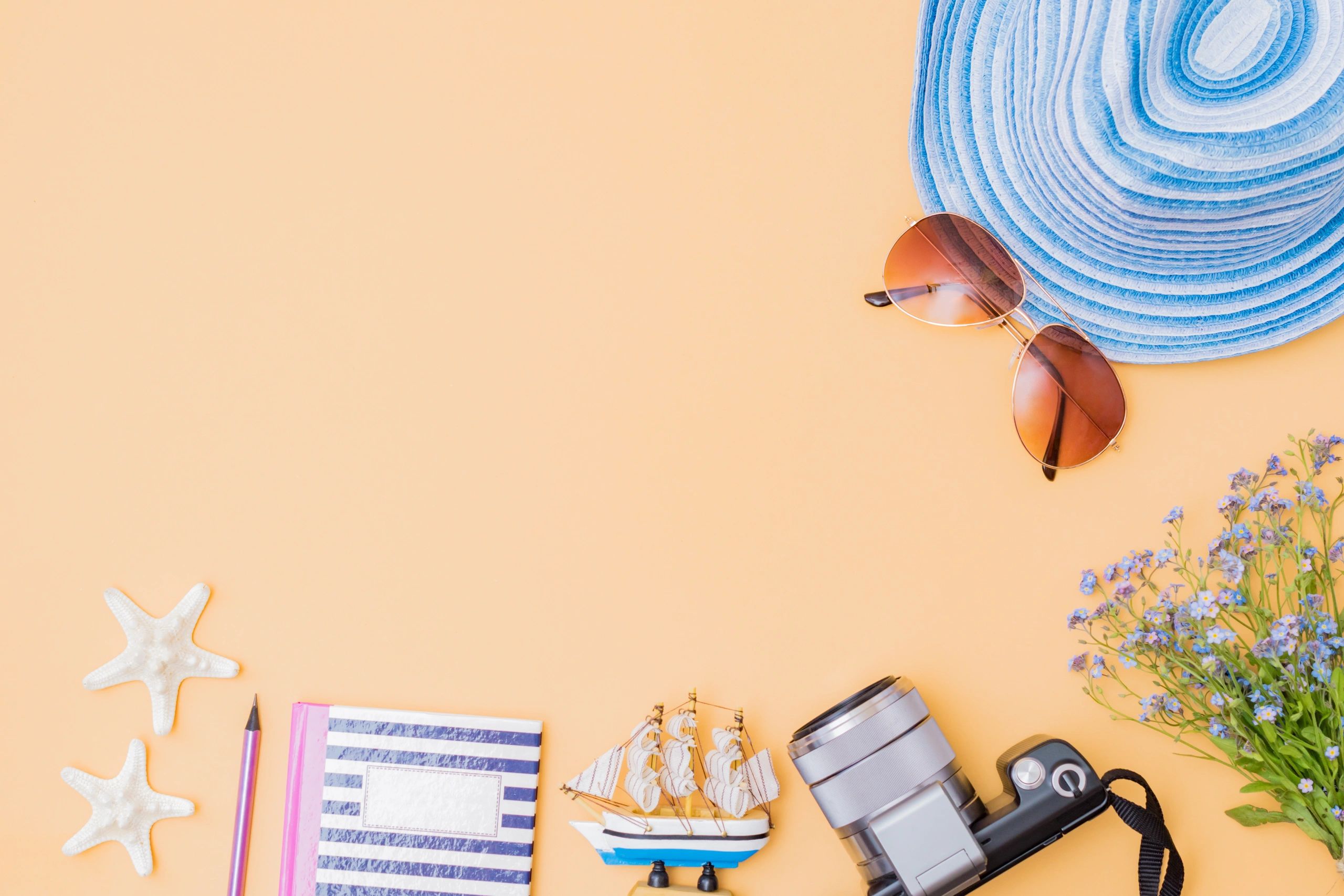 Summer travel flat lay with hat and glasses on yellow background